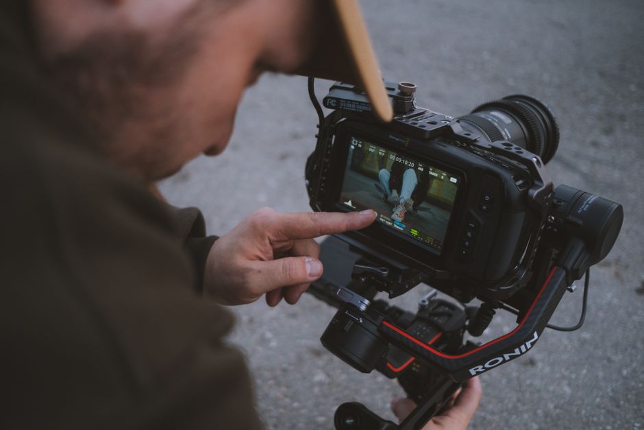 Camera operator reviewing footage on a screen with focus on filmmaking equipment.