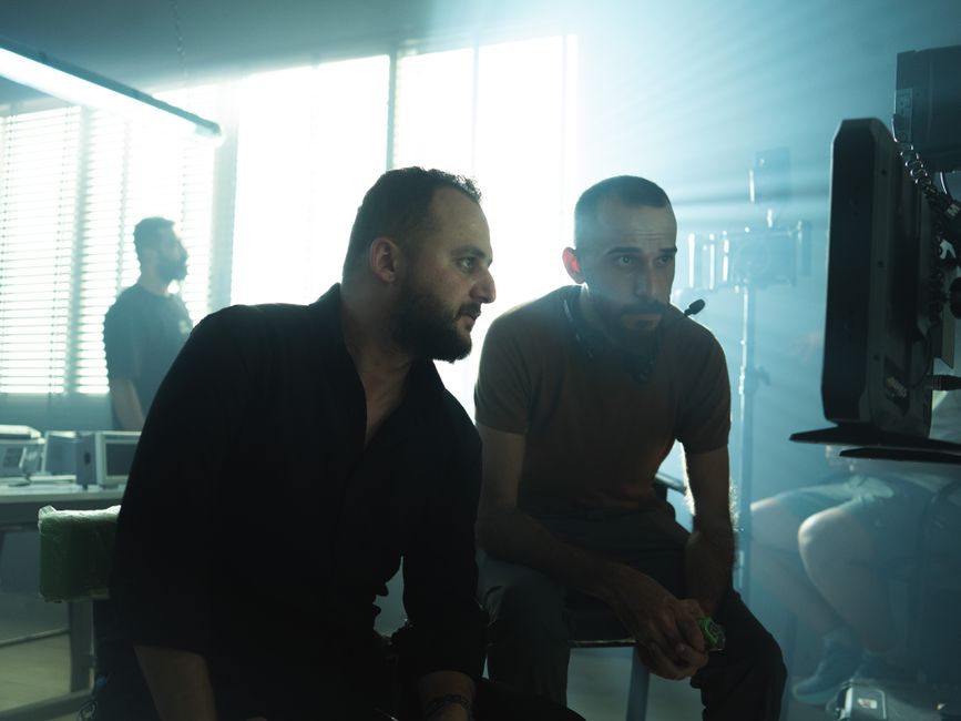 Film crew members collaborating in a Baghdad studio with dramatic lighting.