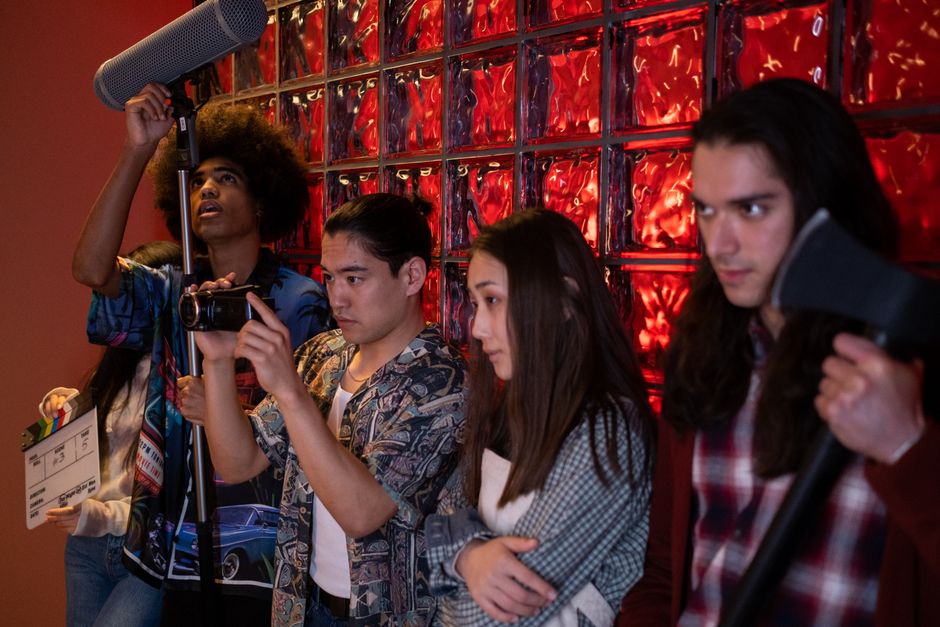Group of teens pretending a movie scene in an indoor setting, showcasing diversity and creative teamwork.