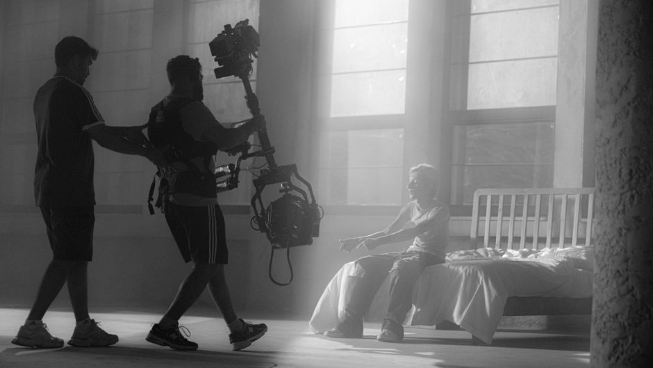 Filmmakers using camera rig for artistic shot in moody setting with dramatic lighting.