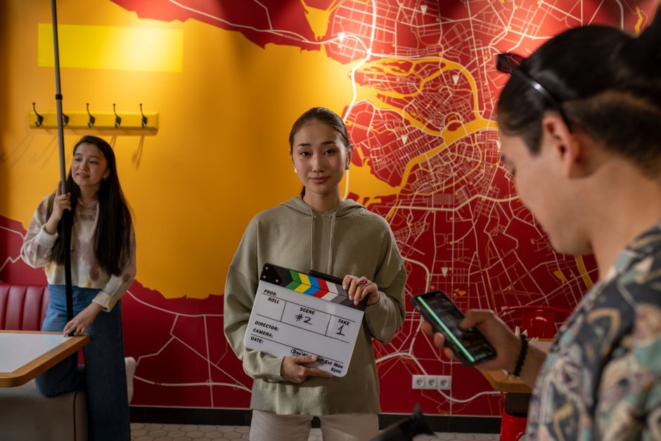 Young film crew in a vibrant indoor setting preparing for a shoot with a clapperboard, set against a city map backdrop.