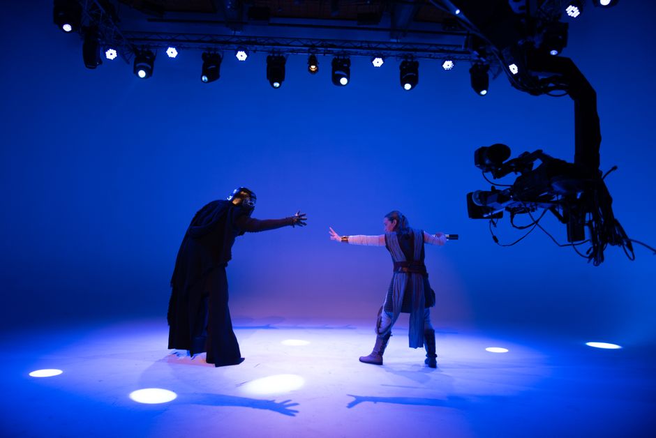 Actors perform a sci-fi scene under bright studio lights with advanced filming technology.