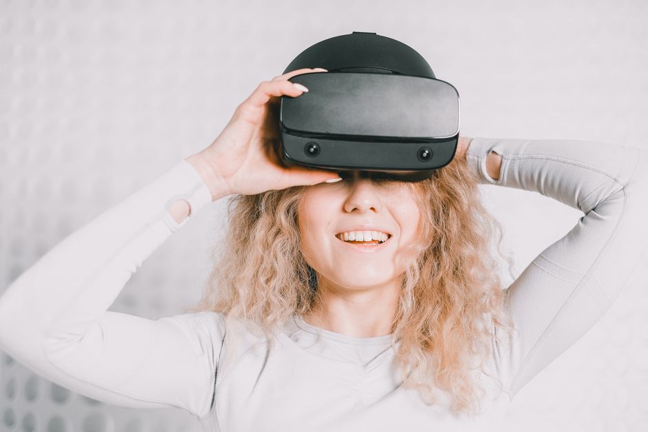 Smiling woman wearing a VR headset and experiencing virtual reality excitement.
