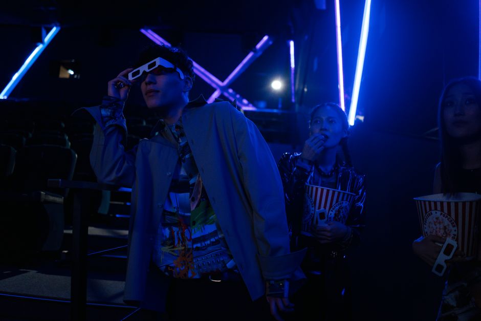 Friends at a movie theater enjoying a night out with popcorn and 3D glasses.