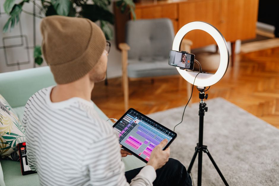 Man using a tablet for video recording with a ring light at home. Capturing digital content creatively.