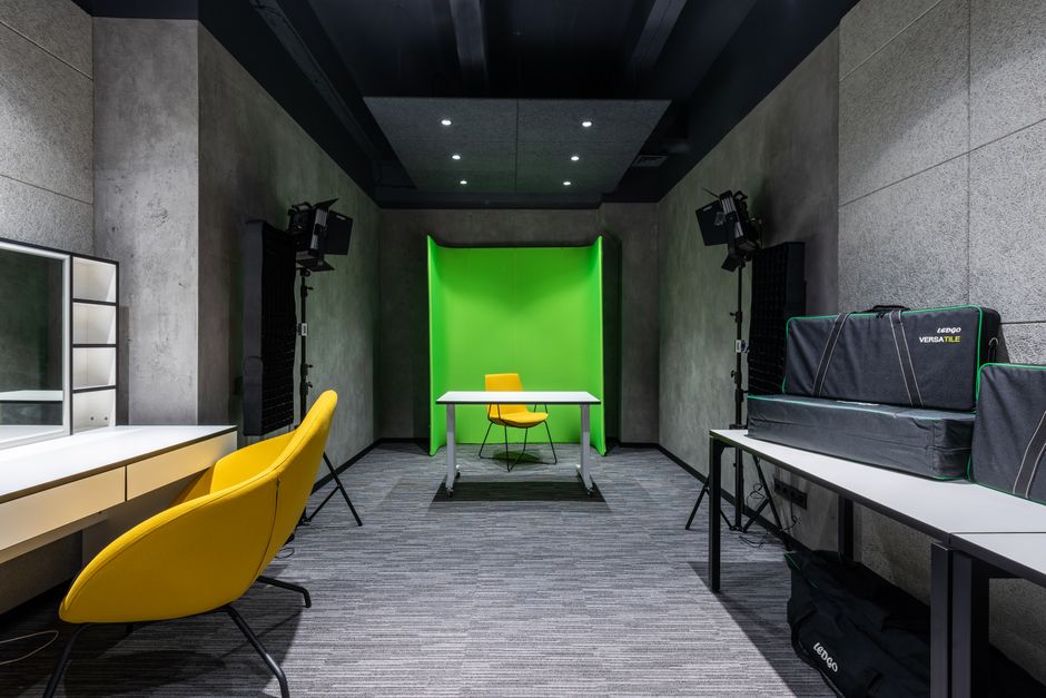 Yellow chair at table placed near green background in spacious contemporary studio with lightning supply and professional appliances on desks