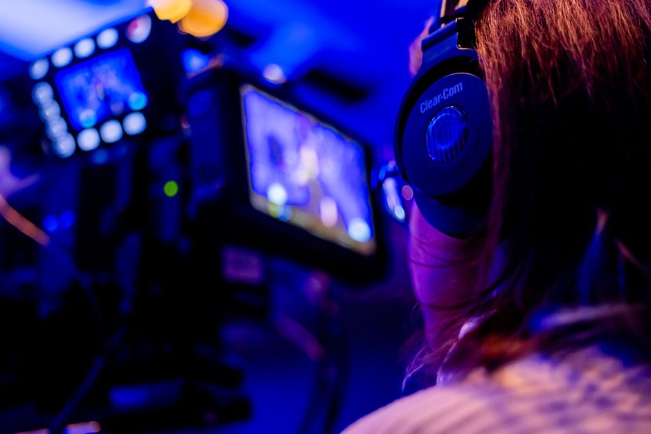 A person wearing headphones operates a camera in a vibrant studio environment.
