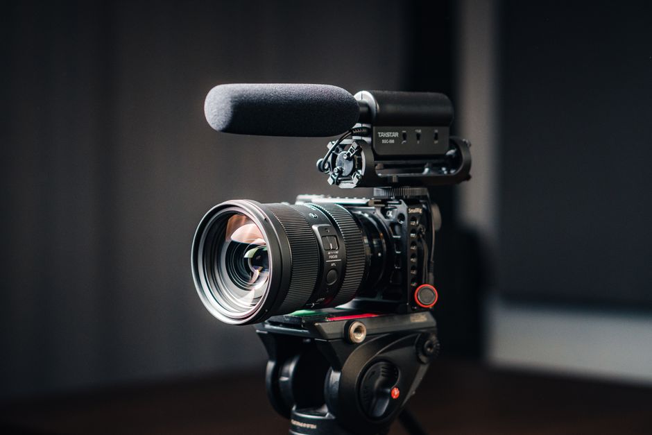 Close-up of a professional video camera with a mounted microphone on a tripod.
