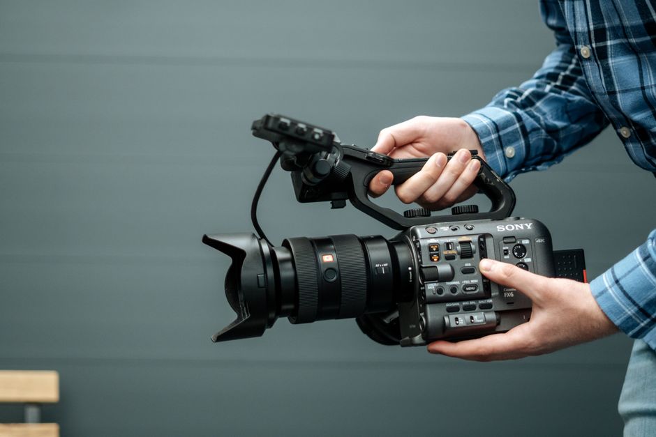 Close-up of a person handling a professional video camera indoors, emphasizing modern film equipment.