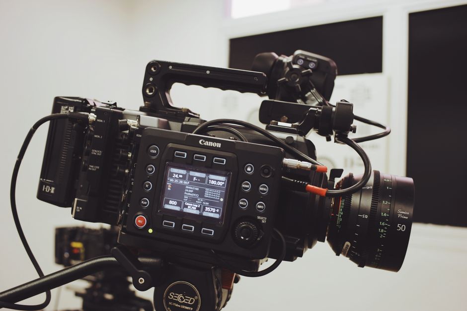 Close-up of a professional video camera setup on a tripod, ready for filming in a studio environment.