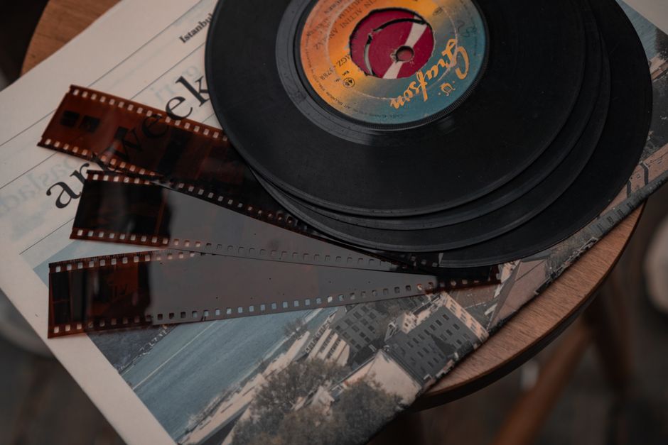 Stack of vintage vinyl records and film negatives on a wooden table.