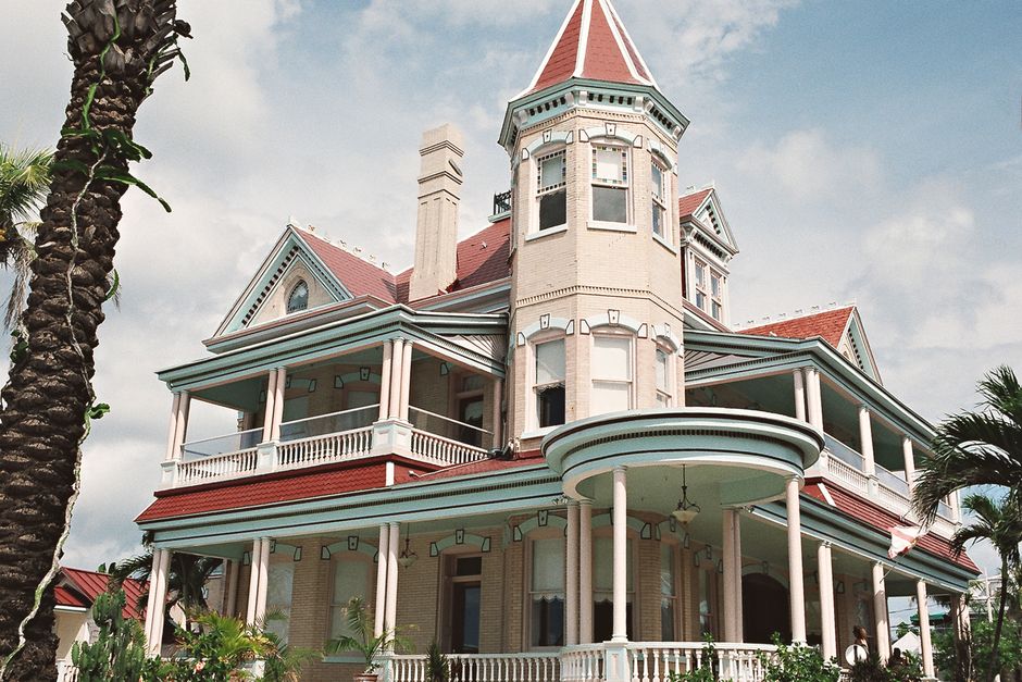 Beautiful colonial architecture house in Key West under a clear blue sky, with palm trees surrounding it.