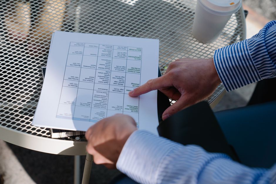 Professional reviewing a document outdoors at a table during a business meeting.