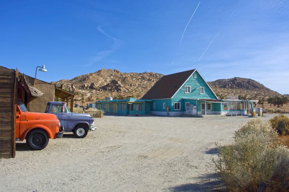 Blue house in a rural, arid landscape with vintage trucks in Lancaster, CA.
