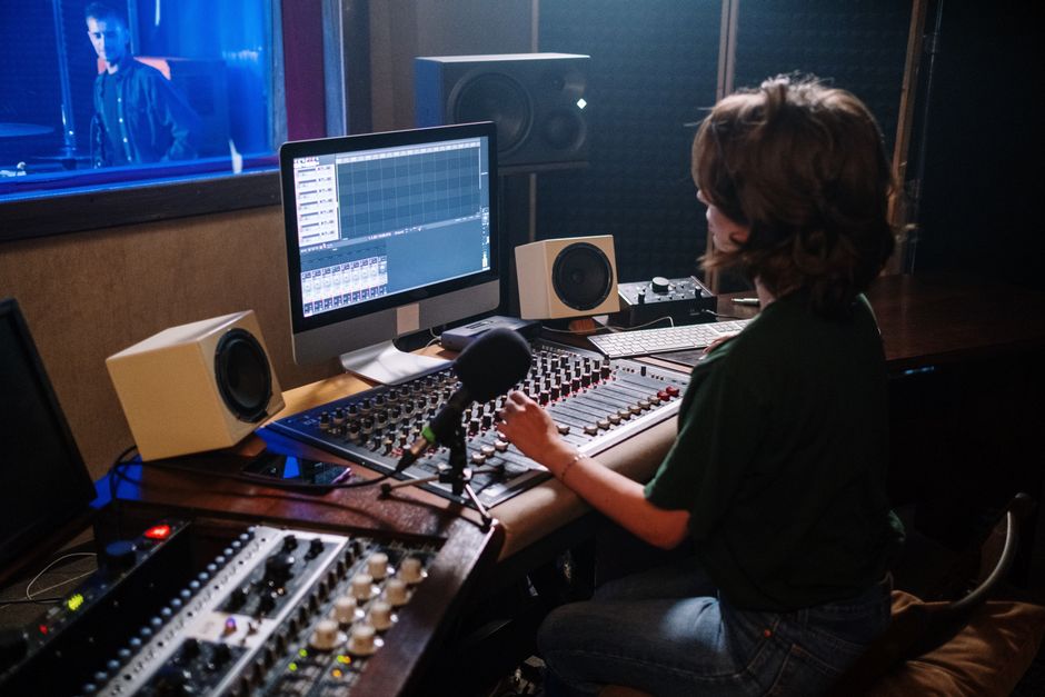 Sound engineer working at a modern recording studio with mixing equipment and computer.