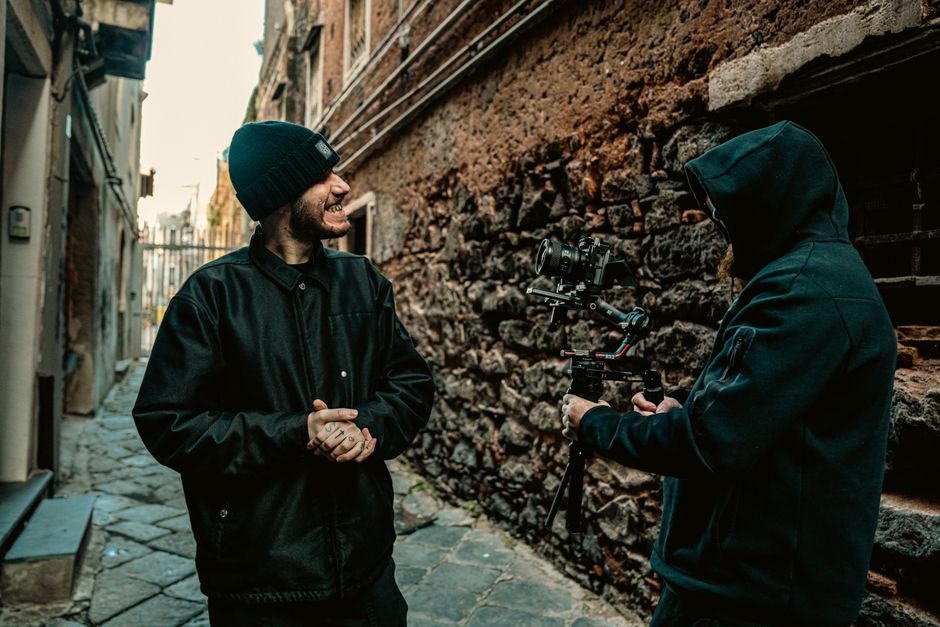 Two men filming on city streets with a gimbal in Catania, Sicily, Italy.
