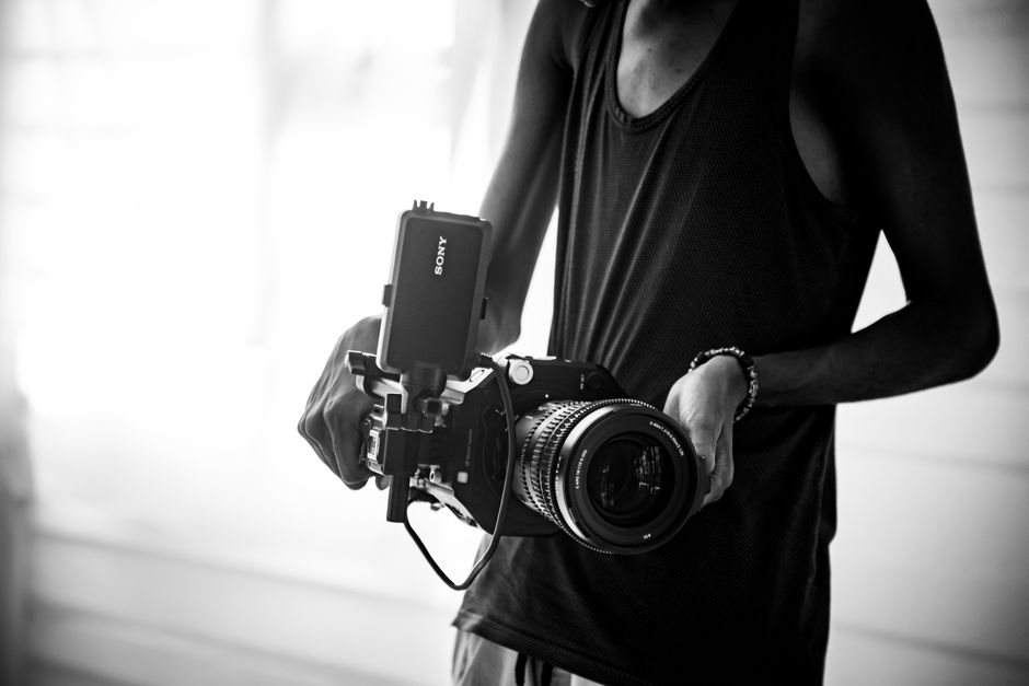 Monochrome image of a photographer holding a professional camera rig indoors.