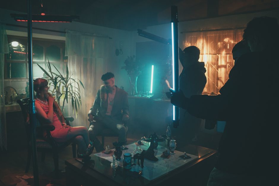 Cinematic scene with neon lights and actors on set, creating a mysterious atmosphere.
