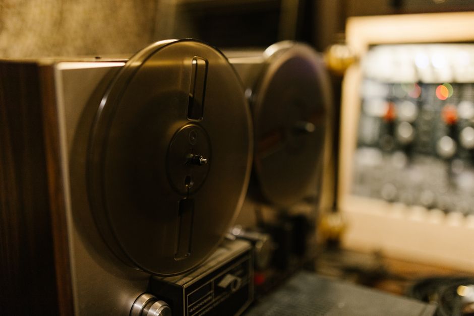 Close-up of a vintage tape recorder in a professional recording studio setting.