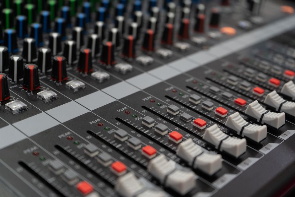 Close-up of a professional audio mixer showcasing control dials and sliders used in sound mixing.