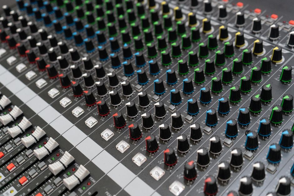 Detailed image of an audio mixer with colorful knobs and controls in a studio setting.