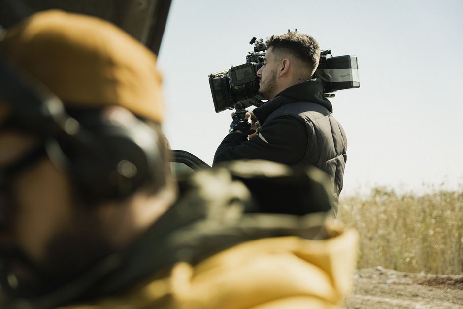 Cameraman recording in an outdoor rural area with professional equipment.