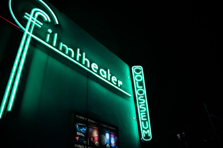 Vibrant neon film theater sign glowing at nighttime.