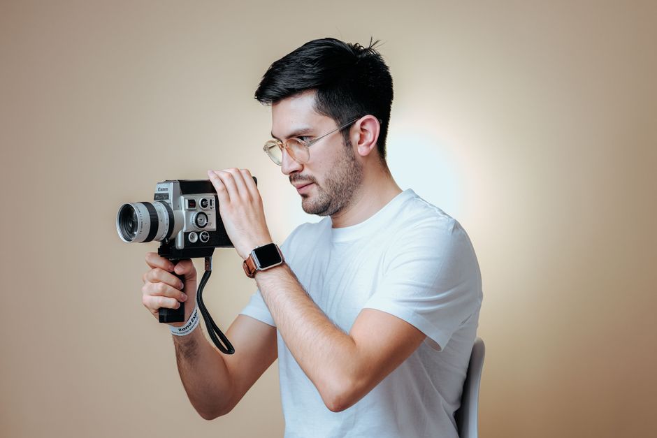Man holding a vintage camera in a studio setting, creating a retro vibe.