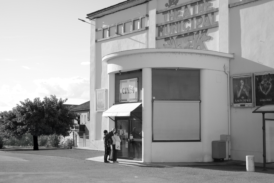 Retro theater entrance with patrons in black and white, evokes a classic cinematic feel.