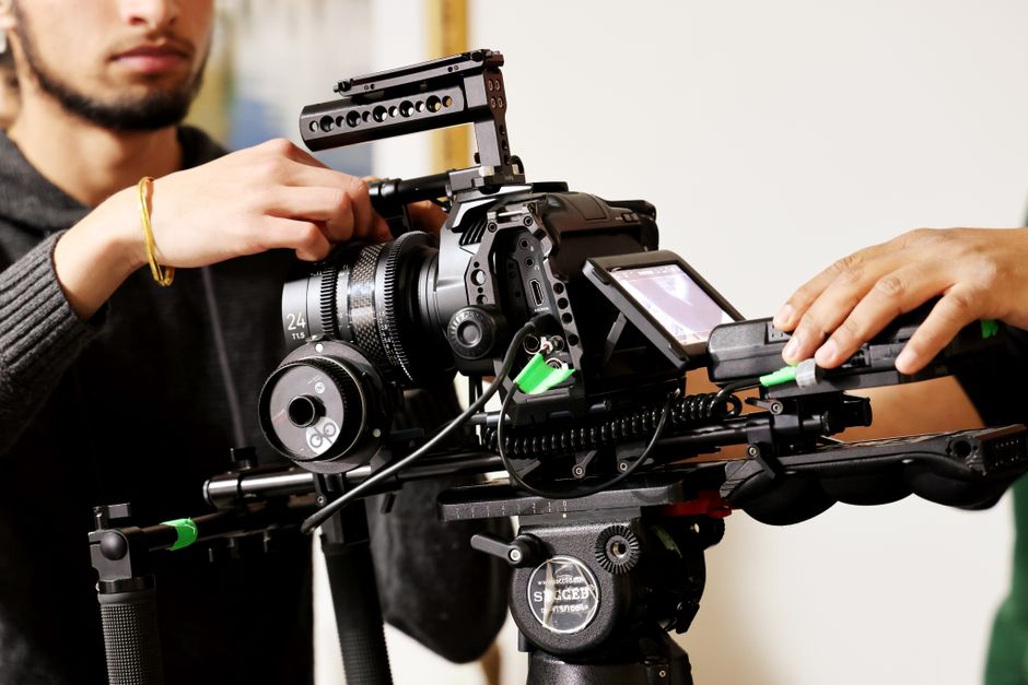 Professional videographers making adjustments on a high-end camera rig indoors for a film project.