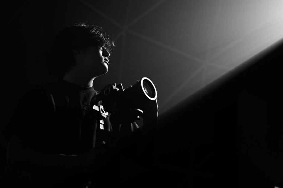 Silhouette of a person holding a camera with dramatic lighting.