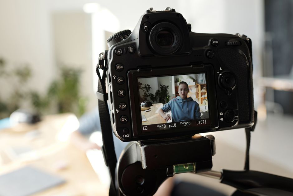 Closeup of DSLR capturing a young adult indoors during daytime. The display shows the portrait in focus.
