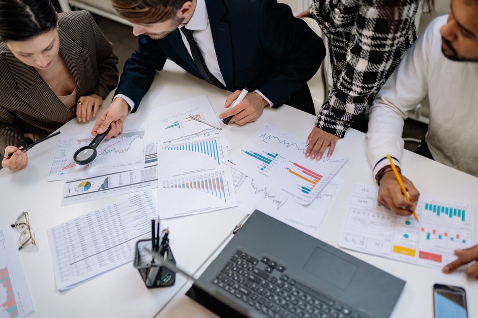 A group of professionals reviewing financial charts in an office meeting setting.