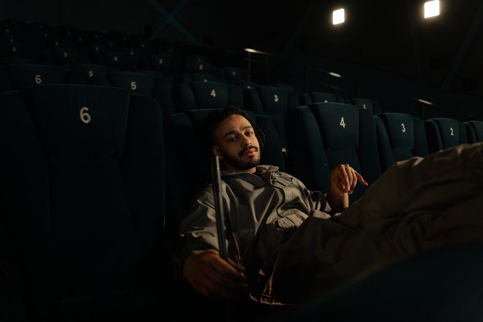 Man in uniform resting on cinema seats during a quiet moment at work.