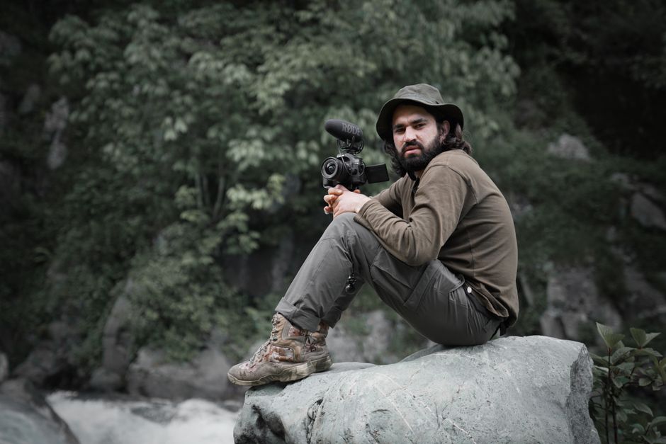 Candid shot of a man photographing nature with a DSLR camera.