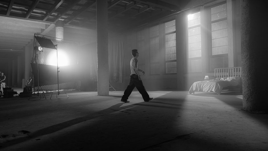 Black and white industrial scene with dramatic lighting and a person walking indoors.