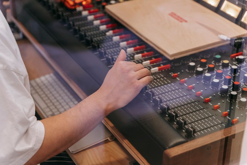Close-up of an audio engineer's hand adjusting a mixing console in a recording studio.
