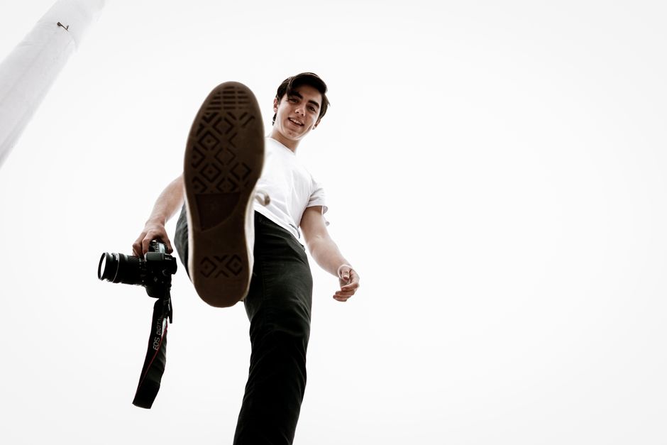 A young male photographer with a camera in a striking low angle shot.