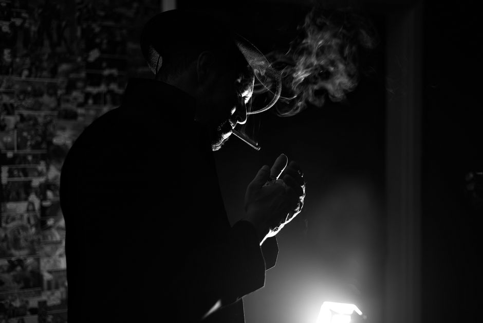 Silhouette of a mysterious man smoking with dramatic lighting in black and white.