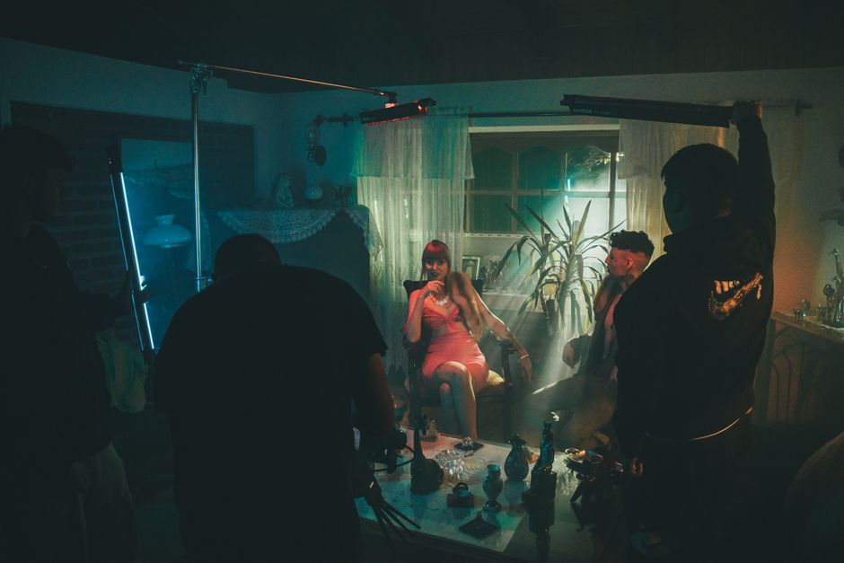 A stylized film set scene with people in a dimly lit room, creating a cinematic atmosphere.