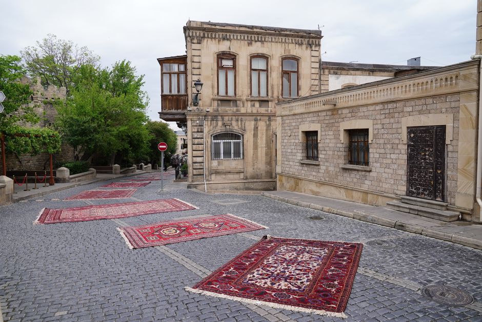 A quiet street in Baku with traditional Azerbaijani carpets displayed on the cobblestones.