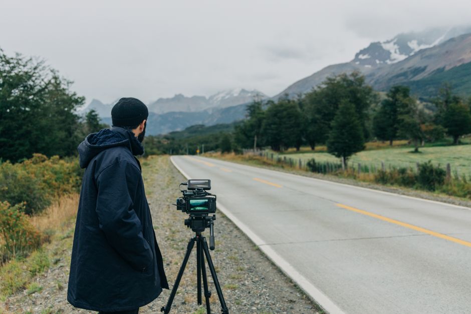 Man with camera on tripod capturing scenic roadside mountains in Chile.