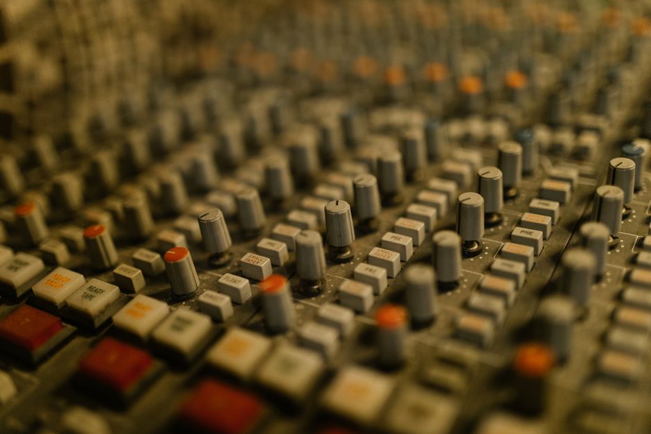 Detailed view of audio mixing knobs and sliders in a recording studio setting.