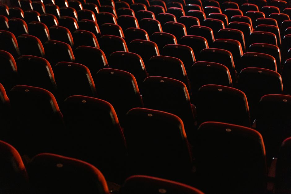 A view of empty red theater seats lit softly, showcasing the quiet ambiance of a cinema.