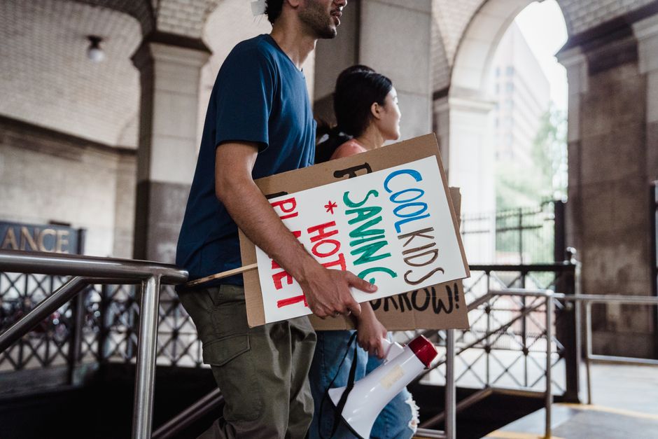 Young people marching with signs advocating for climate change action. Urban setting, daytime protest.