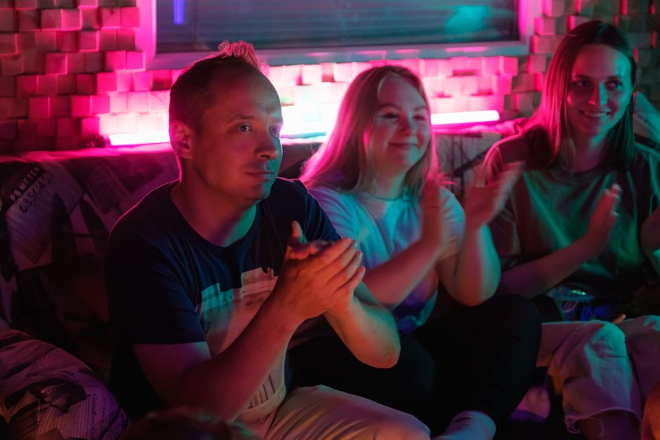 A lively group of adults enjoying a vibrant indoor event, illuminated by neon lights.