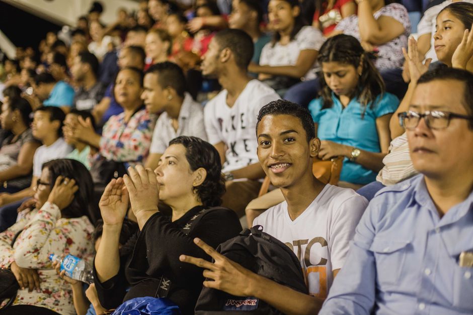 A diverse group of spectators attending a live event indoors, expressing joy and excitement.
