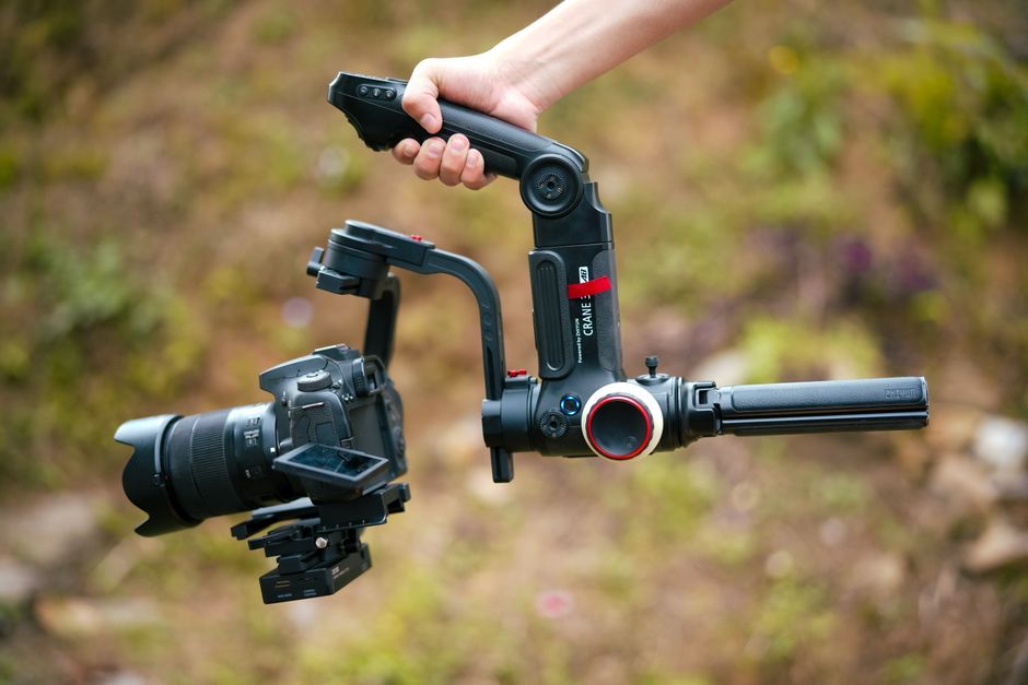 Close-up of a camera on a gimbal stabilizer held outdoors, showcasing photography equipment.
