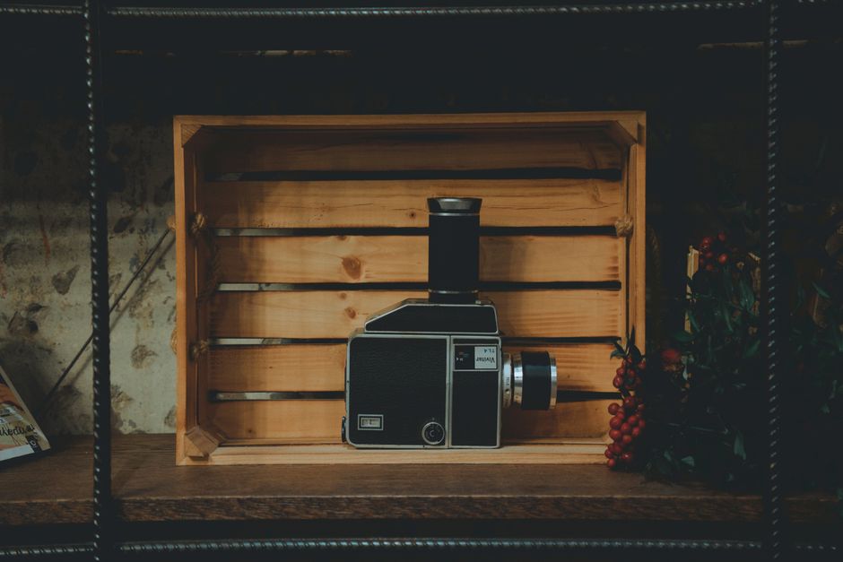 A vintage camera placed in a wooden crate, set against a rustic background with subtle lighting.