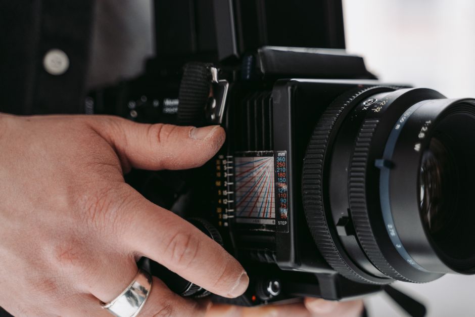 A photographer holds a medium format camera, showcasing intricate details.